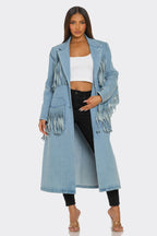 Woman wearing a long denim coat with fringe details on a white background