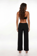 Woman wearing a black halter top and wide-leg pants on a white background