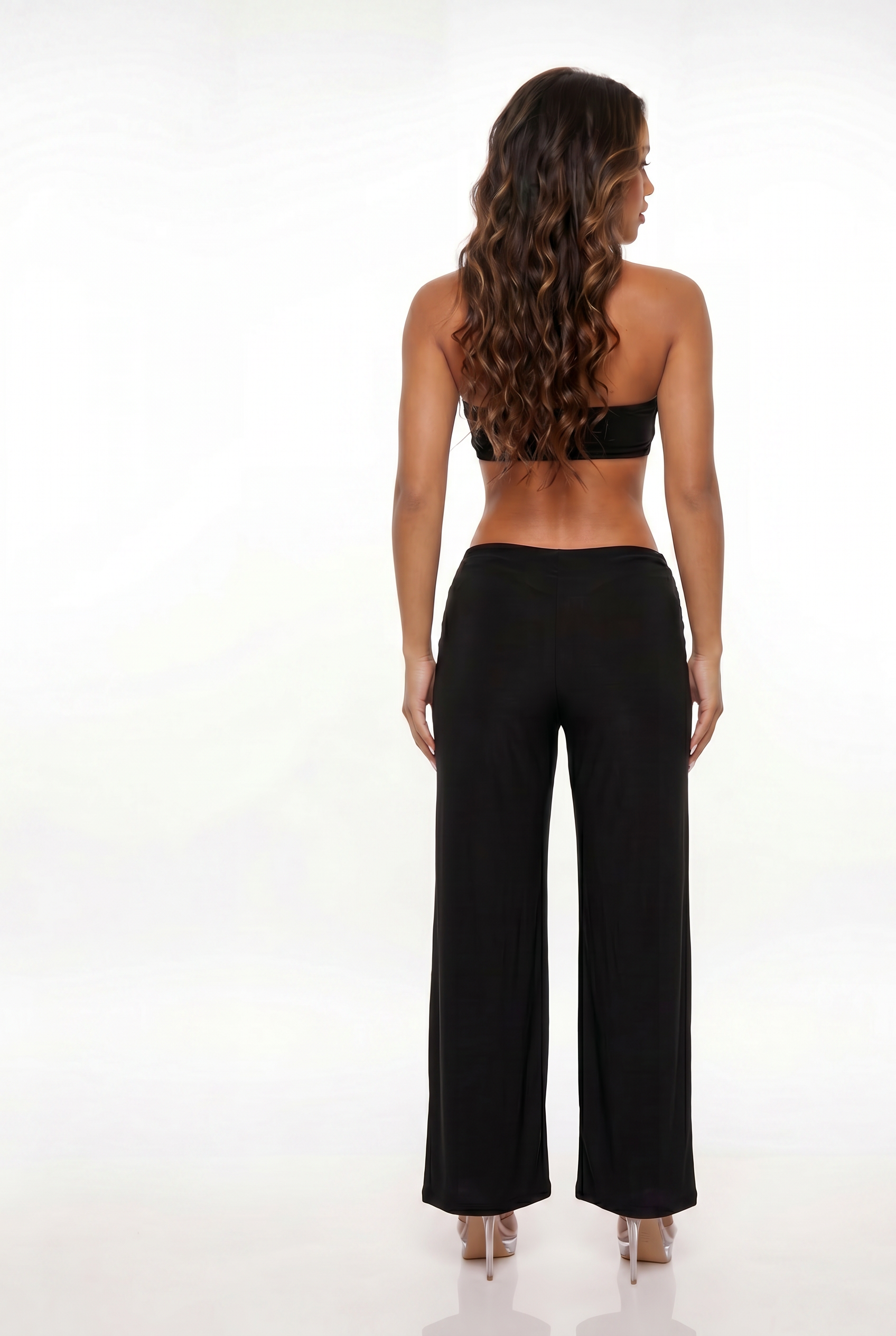 Woman wearing a black halter top and wide-leg pants on a white background