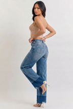 Woman wearing high-waisted blue jeans and a sheer top on a white background