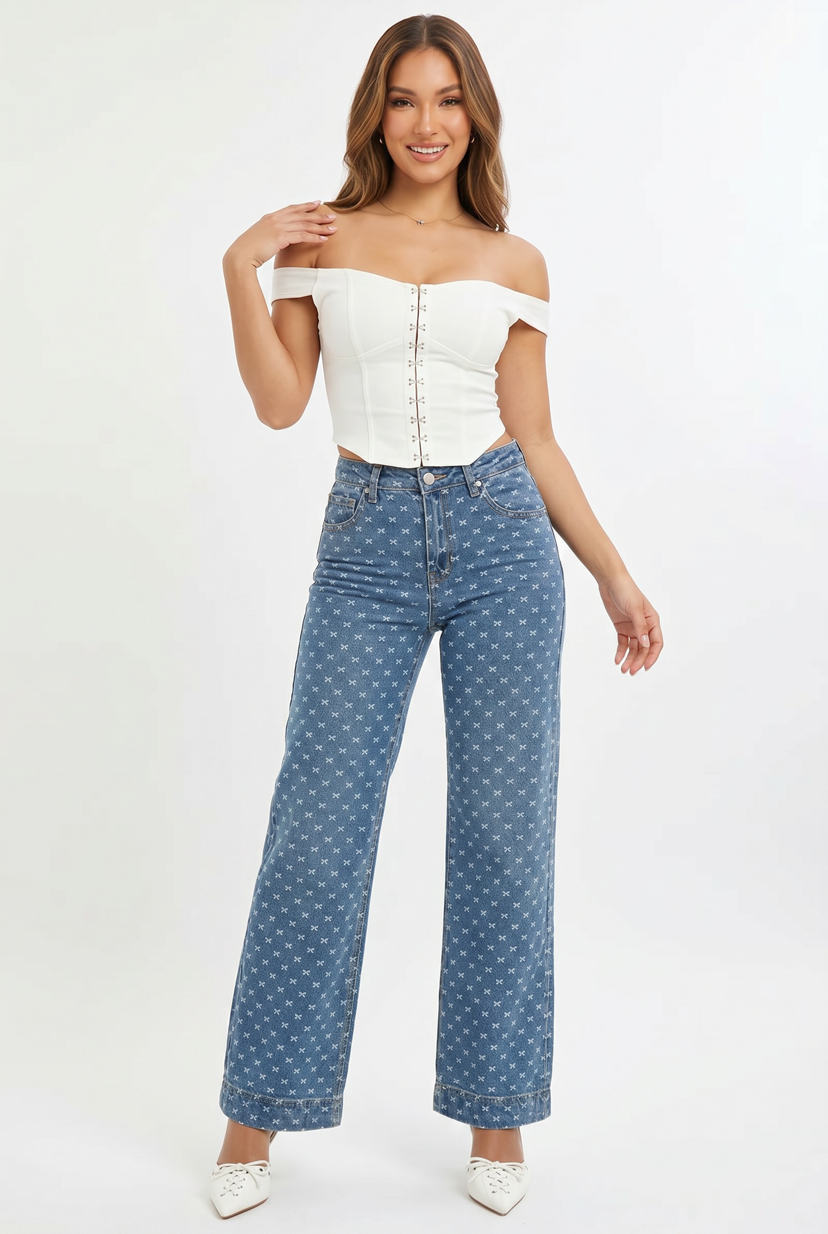 Woman wearing a white off-shoulder top and blue polka dot jeans on a white background