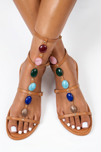 Collage of multiple pairs of sandals with colorful embellishments on a white background