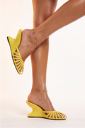 Yellow high-heeled shoes worn by a person on a light background