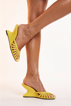 Yellow high-heeled shoes worn by a person on a light background