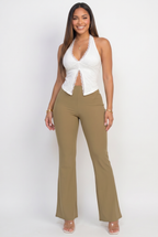 Woman wearing a white halter top and beige pants on a white background