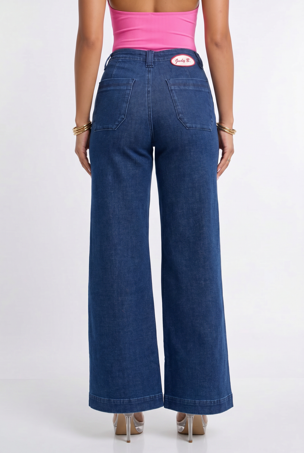 Person wearing blue wide-leg jeans and a pink top on a white background