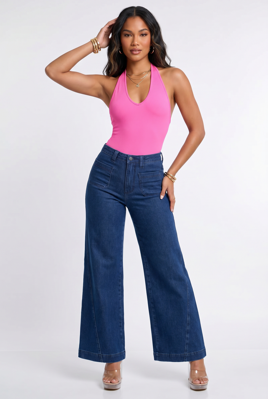 Woman wearing a pink halter top and blue jeans on a white background