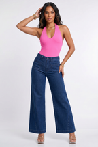Woman wearing a pink halter top and blue jeans on a white background