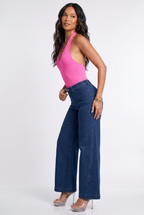 Woman wearing a pink halter top and blue jeans on a white background