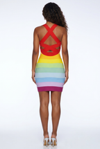 Woman wearing a colorful dress with a red backless top and multicolored skirt on a white background