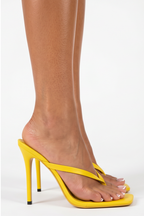 Yellow high-heeled sandals worn by a person on a white background
