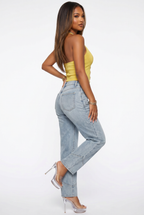Woman wearing a yellow top and light blue jeans on a white background