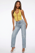 Woman wearing a yellow sleeveless top and light blue jeans on a white background
