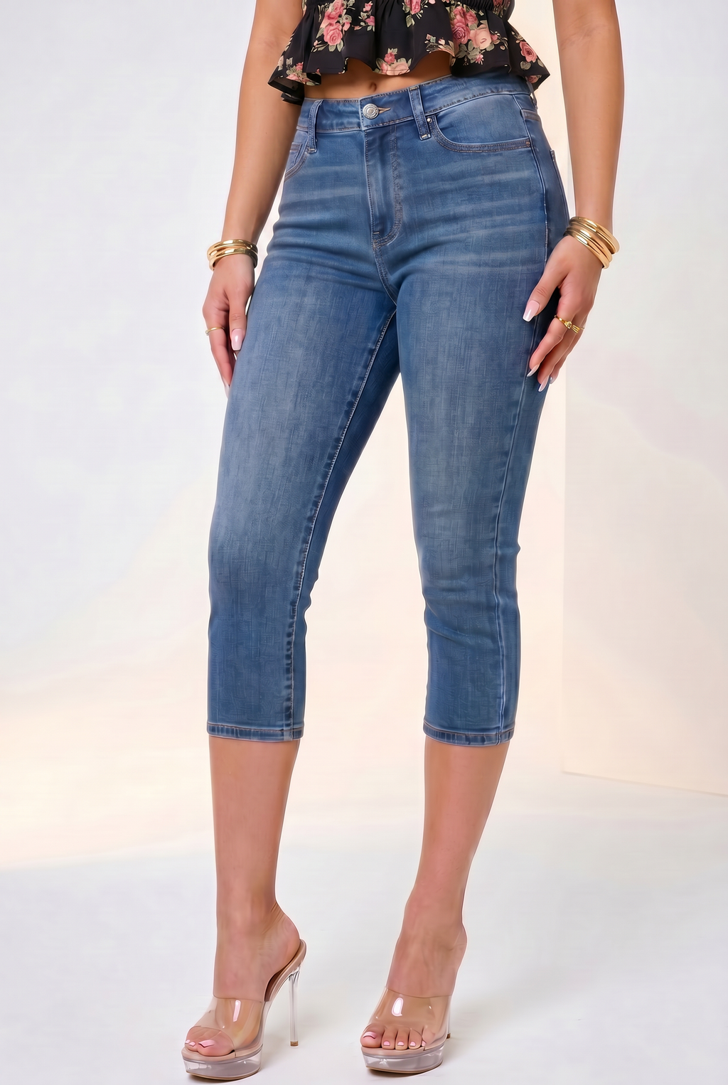 Person wearing blue jeans and a floral top on a plain background