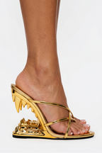 Gold high-heeled sandal with unique design on a white background
