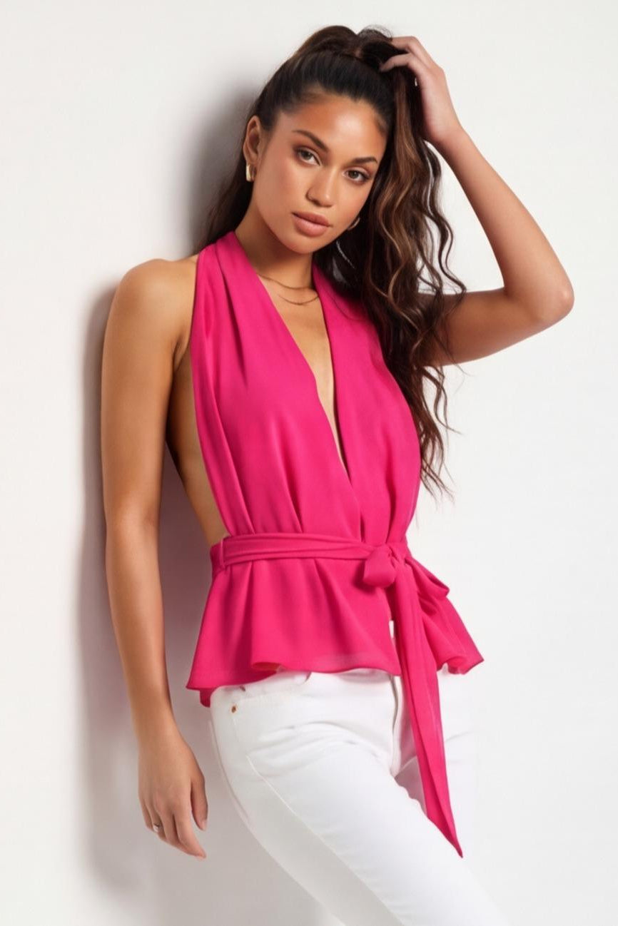 Woman wearing a bright pink sleeveless top with a plunging neckline and tied waist, standing against a light background.