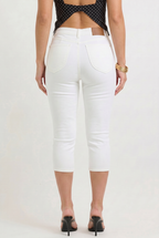 Person wearing white capri pants on a plain background