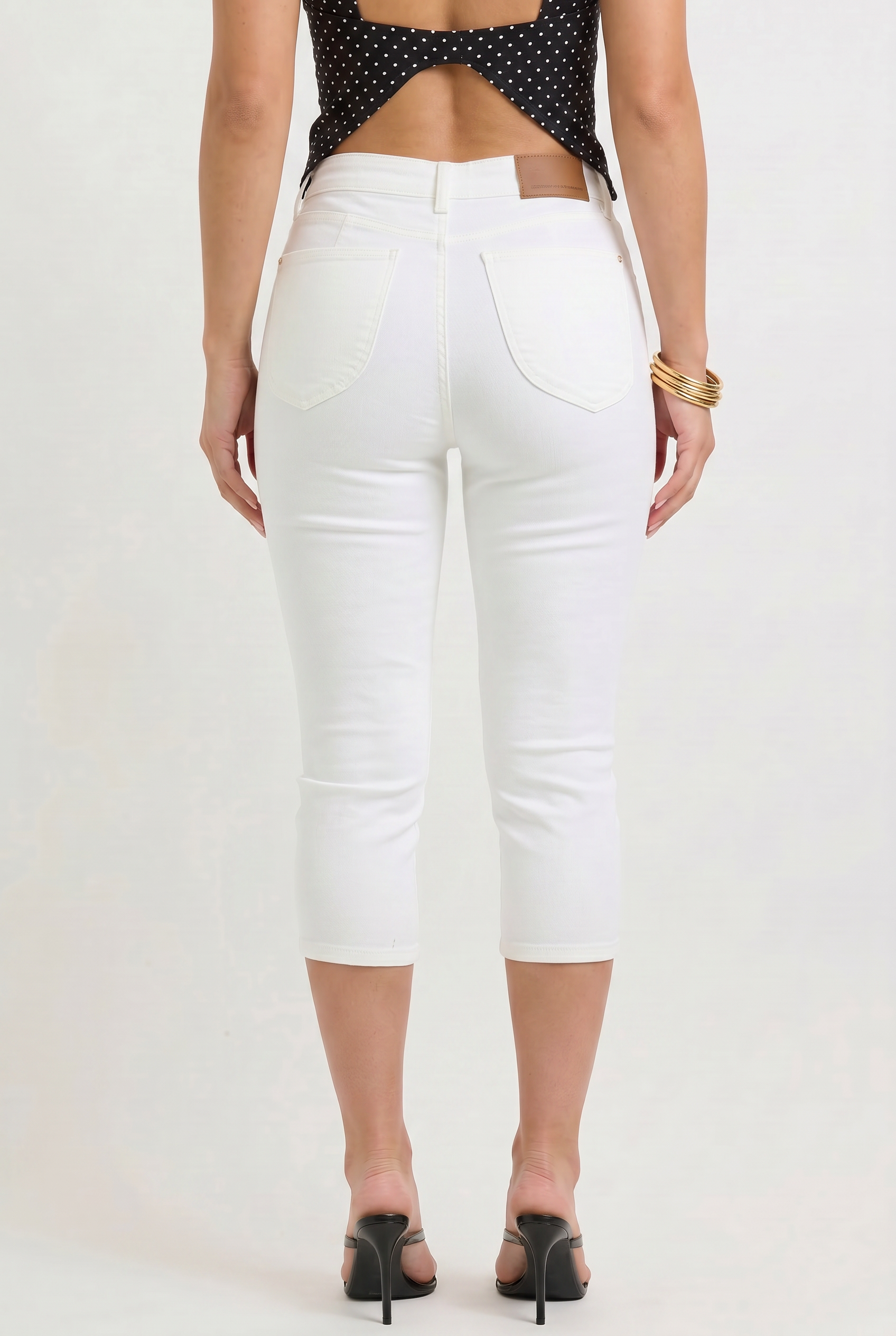 Person wearing white capri pants on a plain background