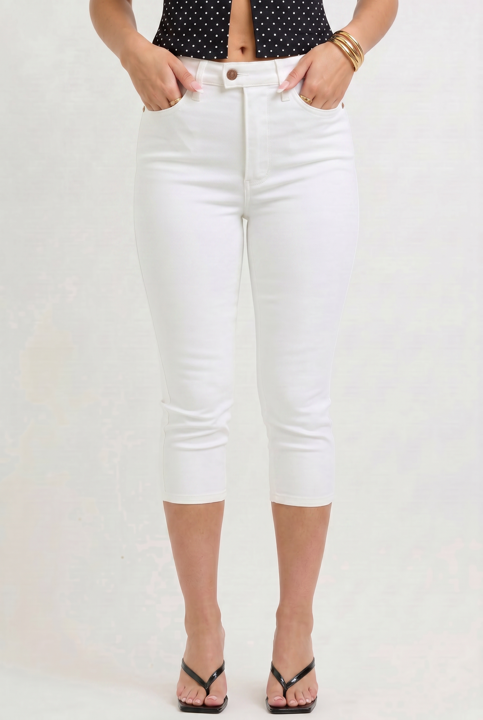 Person wearing white jeans and a black polka dot top on a plain background